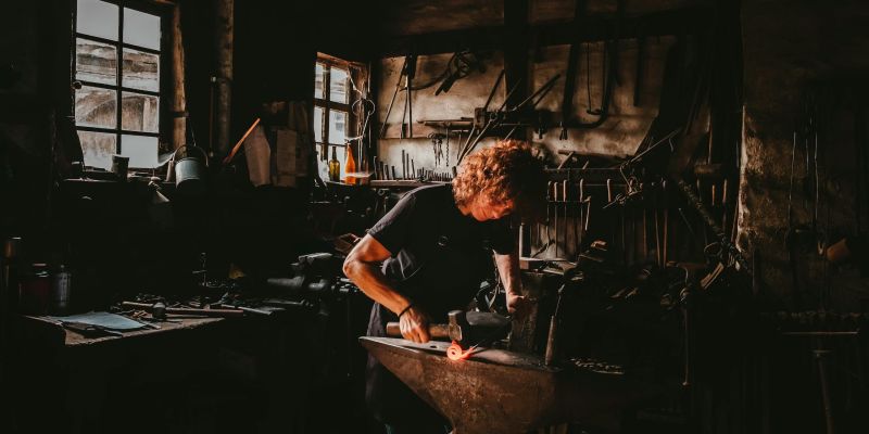 Blacksmith working at an anvil with sparks, representing artisan and lifestyle video production in the Cotswolds