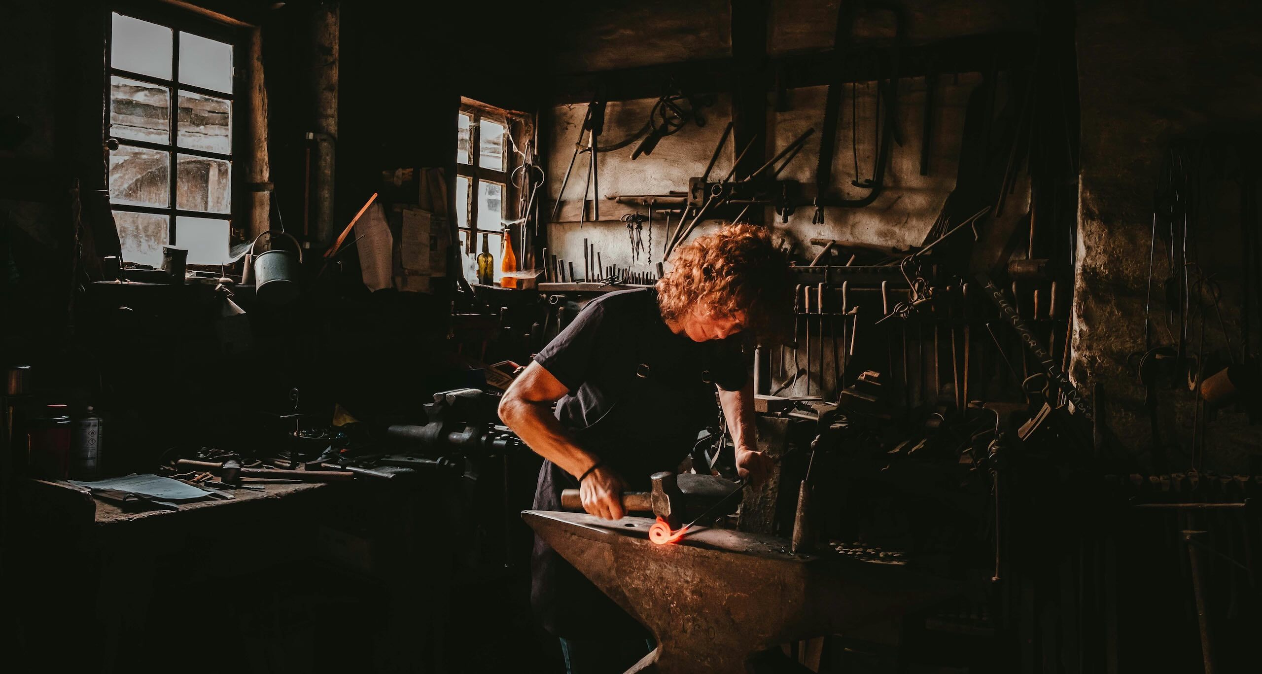 Blacksmith working at an anvil with sparks, representing artisan and lifestyle video production in the Cotswolds
